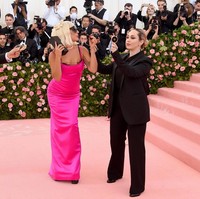 Tak hanya untuk memegangi gaunnya, Lady Gaga juga butuh banyak asisten untuk bergaya di karpet merah. Saat membuka dress bervolumenya dan tampil dengan gaun strappy berikut, dua orang pahlawan setia mendampingi penyanyi tersebut berpose. Foto: Getty Images