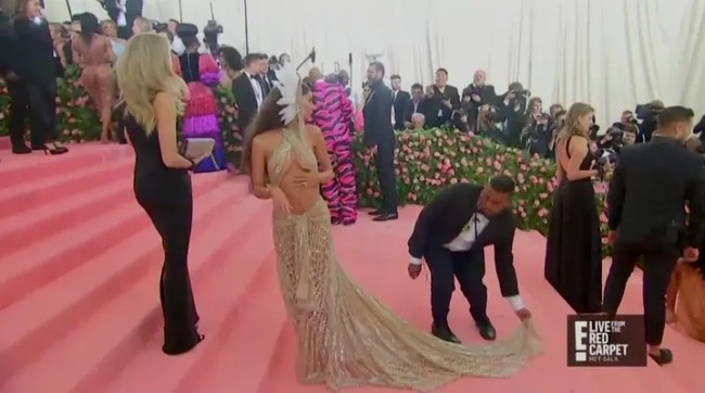Kerepotan para pahlawan Met Gala tentu lebih dari yang tertangkap di kamera paparazi. Hal itu pun bisa diliha dalam tayangan siaran langsung karpet merah. Agar siluet gaun Emily Ratajkowsky terlihat sempurna, seorang pria harus mengawasi dan membetulkan ekornya. Foto: dok E!