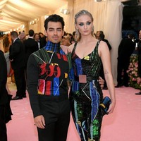 Sophie menebar pesonanya dengan jumpsuit edgy penuh warna dari Louis Vuitton. Joe pun tampil serasi dengan turtleneck berwarna senada. (Foto: Getty Images)