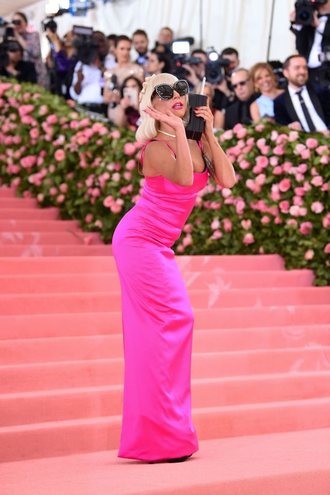 Penampilan Gaga lalu berubah lagi di MET Gala 2019. Kali ini, ia memakai column dress berwarna pink neon yang dipadu dengan oversized sunglasses.  (Foto: Getty Images)