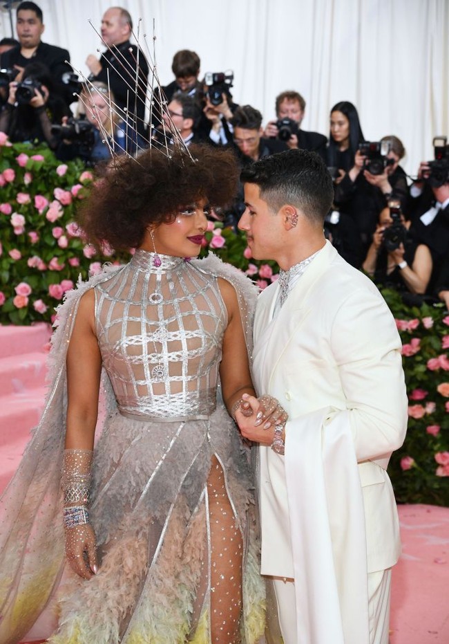 Priyanka memesona dengan gaun silver berdetail bulu dari Dior. Sementara Nick tampak gagah dengan tuksedo putih bergaya India, juga dari Dior. (Foto: Getty Images)