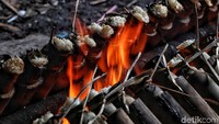 Pekerja memanggang bambu-bambu yang telah diisi dengan ketan, santan kelapa, dan garam.