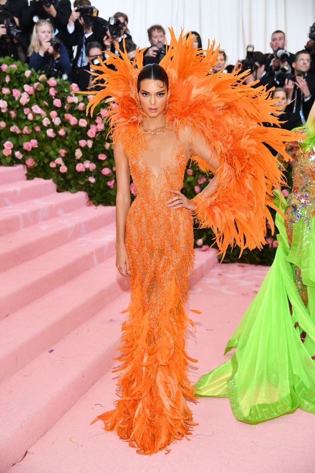 Kendall Jenner juga menampilkan gaya Hollywood klasik dalam balutan gaun plunging neckline dari Versace. Penampilan serba oranye tampak dramatis dengan detail bulu raksasa di bagian belakang dan bawah gaun. Foto: Dimitrios Kambouris/Getty Images