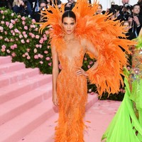 Kendall Jenner juga menampilkan gaya Hollywood klasik dalam balutan gaun plunging neckline dari Versace. Penampilan serba oranye tampak dramatis dengan detail bulu raksasa di bagian belakang dan bawah gaun. Foto: Dimitrios Kambouris/Getty Images