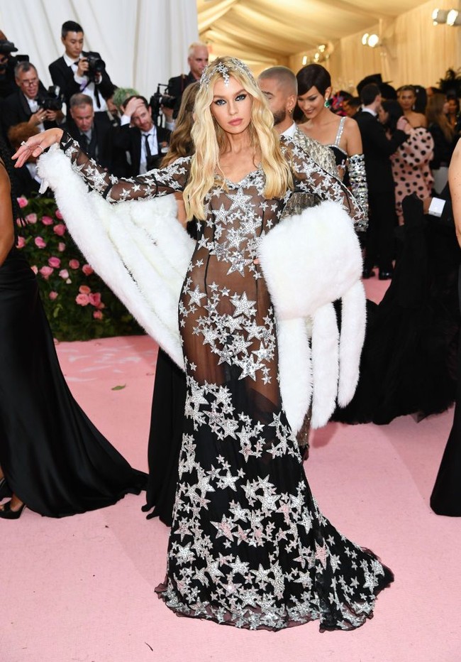 Stella Maxwell tampil seksi bergaun hitam transparan dari brand Moschino. Naked dress Stella tampil meriah berkat detail bintang-bintang dan aksesori bulu. Foto: Dimitrios Kambouris/Getty Images