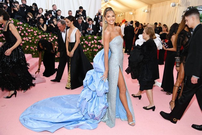 Candice Swanepoel tak kalah seksi berbalut gaun high-slit biru rancangan Atelier Prabal Gurung. Keseluruhan gaun bertaburan payet dan terkesan dramatis berkat train panjang bervolume. Tatanan rambut kuncir tinggi dengan detail sulur membuat penampilannya seperti jin seksi. Foto: Dimitrios Kambouris/Getty Images