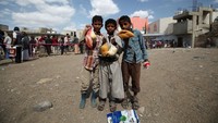 Anak-anak Yaman berpose menunjukkan makanan untuk berbuka puasa usai mengantre di pusat distribusi makanan yang dibuka oleh relawan.