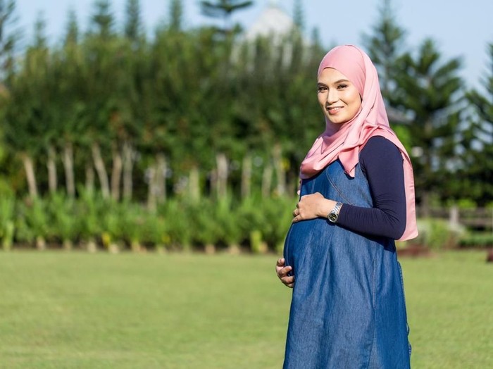 ibu hamil Young pregnant women with blue dress standing and holding belly