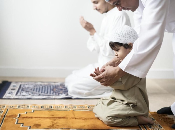 Muslim boy learning how to make Dua to Allah