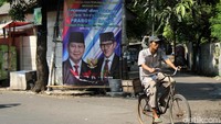 Seorang pengendara sepeda melintas di depan spanduk kemenangan Prabowo-Sandiaga Uno.