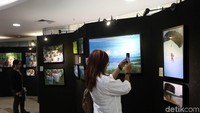 Pengunjung mengabadikan foto-foto yang dipamerkan.