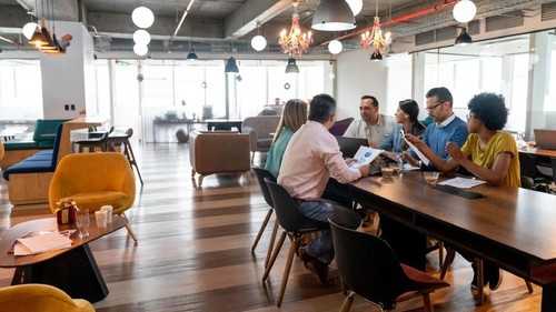 Multi ethnic group of professionals at a coworking office in a meeting discussing something looking focused