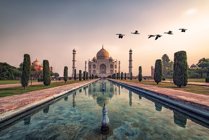 Agra, India - September 21, 2015: Muslim tourists posing for a photograph in one of the two grand red sandstone buildings that mirror each other, and face the sides of the tomb of Taj Mahal Agra India This one is a mosque