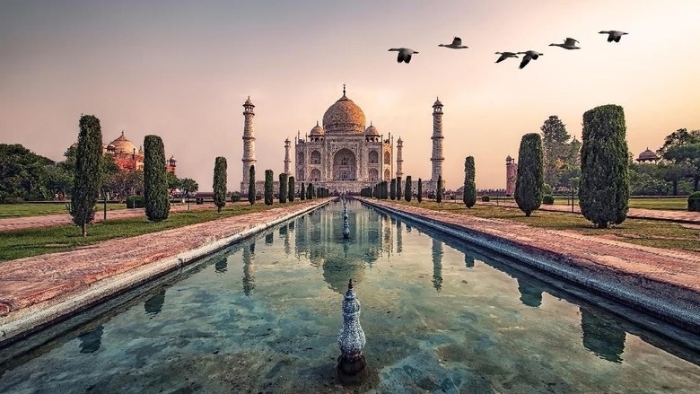 Agra, India - September 21, 2015: Muslim tourists posing for a photograph in one of the two grand red sandstone buildings that mirror each other, and face the sides of the tomb of Taj Mahal Agra India This one is a mosque