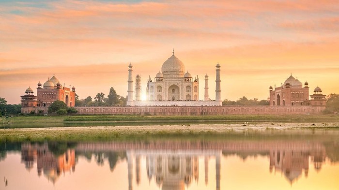 Agra, India - September 21, 2015: Muslim tourists posing for a photograph in one of the two grand red sandstone buildings that mirror each other, and face the sides of the tomb of Taj Mahal Agra India This one is a mosque