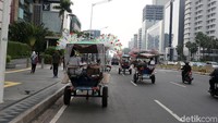 Beberapa delman melintas di antara kendaraan bermotor di Jalan Thamrin.