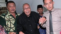 Permadi nampak mengenakan kemeja hitam lengan panjang saat tiba di Mapolda Metro Jaya, Jakarta.