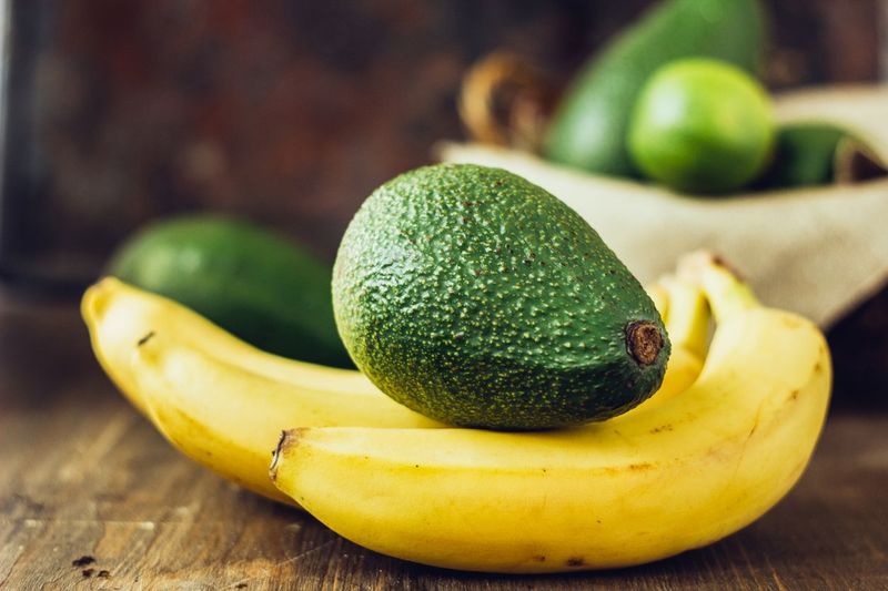 Avocado and banana over brown wooden background