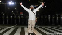 Seorang peserta aksi pose dua jari di depan pagar betis polisi.