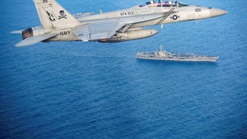 Pesawsat F/A-18E Super Hornet melayang di atasnya. Foto: Reuters