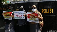 Massa membawa poster-poster tuntutan dan dibentangkan di depan barikade polisi bertameng.