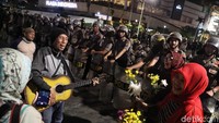 Seorang peserta aksi bahkan bernyanyi dan membagikan bunga.