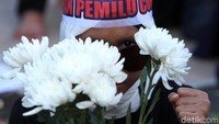 Peserta aksi lawan pemilu curang ini membagikan bunga kepada petugas kepolisian.