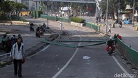 Warga melintas di salah satu jalan yang berada di kawasan Blok A Tanah Abang. Pagar pembatas jalan nampak rusak, meskipun begitu massa aksi telah tak nampak di kawasan tersebut.