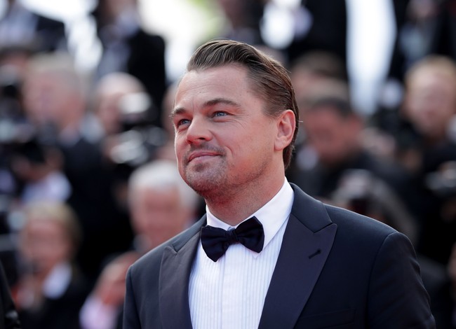 Leo tampak gagah dengan tuksedo berdetail lapel kulit. Ia pun melengkapi penampilan dengan dress shoes hitam mengkilap. Pria 44 tahun tersebut juga memakai kemeja putih berteksur yang dipadukan dengan dasi kupu-kupu. Foto: Getty Images