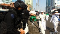 Massa yang mengenakan sorban dan gamis bergerak meninggalkan lokasi kerusuhan.