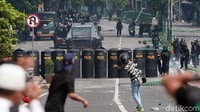Hingga pukul 12.14 WIB sejumlah polisi bersiaga dibalik papan pelindung saat massa aksi melemparkan batu.