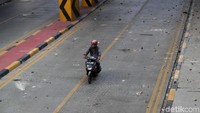 Pengendara motor melintas di salah satu jalan yang berisi batu-batu usai terjadinya bentrok di kawasan Blok A Tanah Abang, Jakarta.