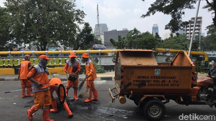 Pasukan oranye atau Petugas Prasarana dan Sarana Umum (PPSU) membersihkan sampah-sampah dan abu sisa bakar-bakaran demo di Jatibaru Tanah Abang, Jakarta.