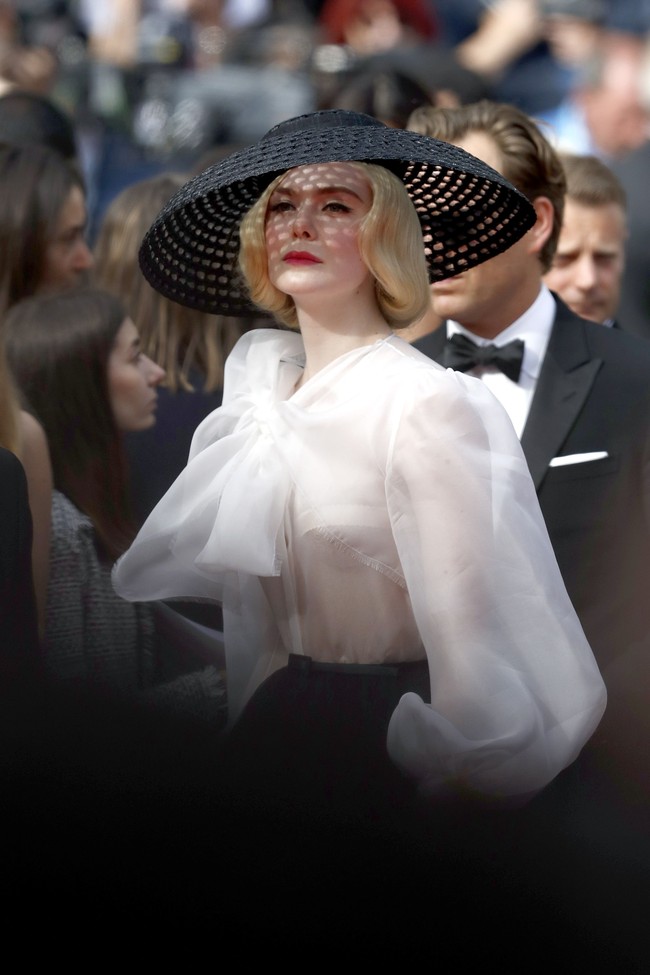 Turut menyempurnakan gaya old Hollywood glam sang bintang Malificenet 2 ini, sebuah topi makrame hitam bertema vintage dengan sepasang heels hitam yang dihiasi tali bersilang. Sebagai sentuhan akhir, lipstik merah merona yang memulas bibir Elle. (Foto: Getty Images)