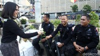 Ia membawa bunga berwarna putih sedangkan rekan lainnya membawa bunga berwarna merah.