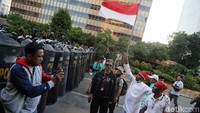 Seorang peserta aksi mengibarkan bendera merah putih sebagai bentuk rekonsiliasi dan perdamaian antara massa dengan polisi di depan gedung Bawaslu, Jakarta.