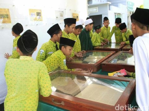 Para siswa sedang melihat Alquran kuno yang dipajang/