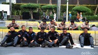 Personel Brimob yang disiagakan di kawasan Bawaslu sedang beristirahat dengan duduk lesehan di Jalan Thamrin.