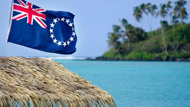 The flag of the Cook Islands, officially known as the Cook Islands Ensign, wave in the wind at Muri Lagoon in Rarotonga, Cook Islands.