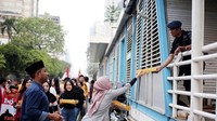 Seorang mahasiswi memberikan makanan kepada personil Brimob yang berjaga di halte bus transjakarta sekitar Gedung Bawaslu. Foto: dok. Aliansi Mahasiswa Cinta NKRI