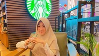 Lagi-lagi mengasup kafein. Tapi kini ia berswafoto tepat di hadapan logo jaringan kedai kopi besar yang ada di berbagai belahan dunia. Foto: Instagram larissachou