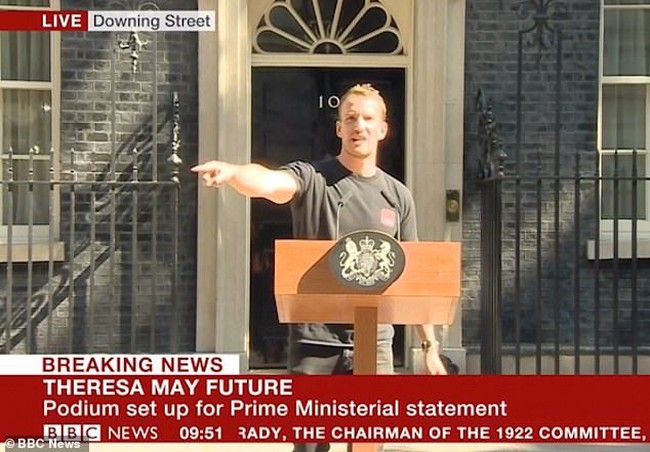 Namanya Tobius Gough. Semuanya bermula ketika aksi Tobius menyetel audip podium terekam kamera TV yang hendak menyiarkan secara langsung pidato Theresa May. Banyak netizen dibuat salah fokus oleh ketampanan wajah Tobius serta badannya yang atletis. Ia pun mendapat julukan the podium guy. (Foto: BBC UK)