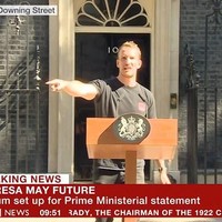 Namanya Tobius Gough. Semuanya bermula ketika aksi Tobius menyetel audip podium terekam kamera TV yang hendak menyiarkan secara langsung pidato Theresa May. Banyak netizen dibuat salah fokus oleh ketampanan wajah Tobius serta badannya yang atletis. Ia pun mendapat julukan the podium guy. (Foto: BBC UK)