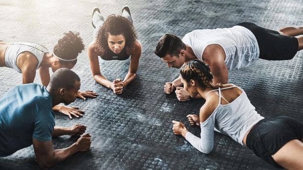 Shot of a group of young people doing planks together during their workout in a gym