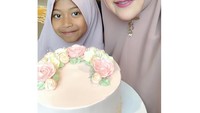 Saat ulang tahun, wanita berhijab ini mendapatkan kejutan kue cantik dengan hiasan buttercream bunga. Ia ditemani sang anak yang terlihat manis dengan hijabnya. Foto: Instagram meggykiwil