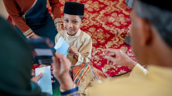 Young boy being presented with a gift of money from his grandparents as part of the Islamic celebration of Hari Raya Aidilfitri (Eid al-Fitr). Kuala Lumpur, Malaysia. May 2018
