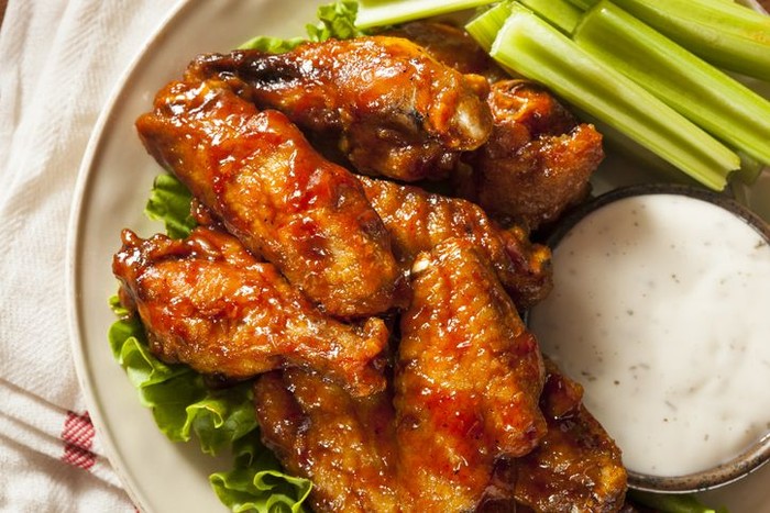 Delicious spicy buffalo chicken wings with beer, celery, carrot sticks and dipping sauces.