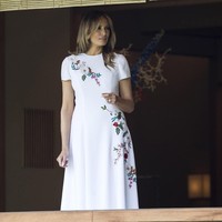 Wanita berusia 49 tahun itu lalu mengganti busananya dengan gaun putih berhias embroidery floral rancangan Carolina Herrera. Gaun seharga 5.847 poundsterling atau Rp 106 juta ini dipakai saat menemui istri Perdana Menteri Jepang, Akie Abe. High heels merah yang menopang kakinya menyempurnakan tribut Melania untuk bendera Jepang lewat busananya. Foto: Getty Images