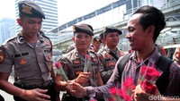 Massa yang tergabung dalam aktivis social media for civic education (SMCE) membagi-bagikan bunga kepada para aparat kepolisian yang berjaga di area sekitar Bawaslu, Jakarta, Rabu (29/5/2019).