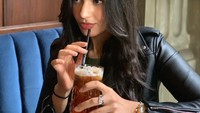 Begini gayanya saat meminum segelas teh leci. Mengenakan jaket kulit, Kareen terlihat lebih dewasa. Foto: Instagram kareenkaur.c